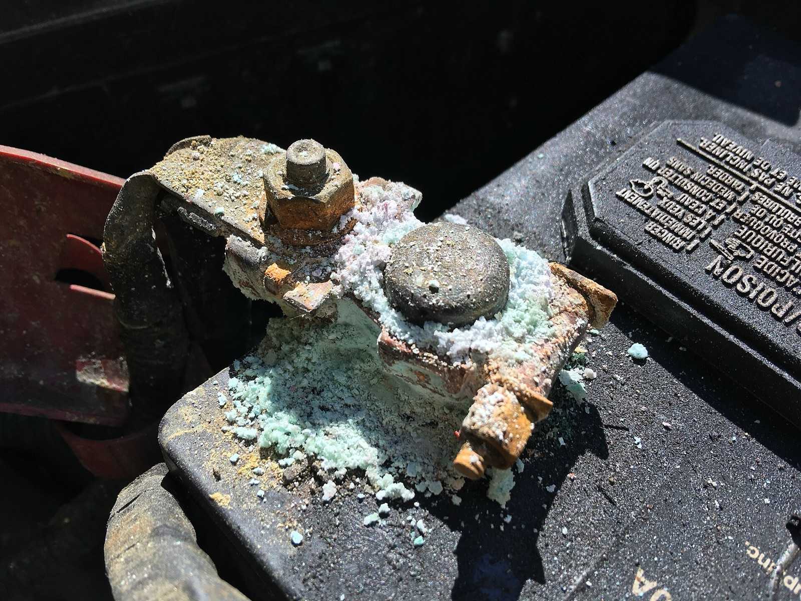 Battery post and clamp heavily coated in white and green corrosion
