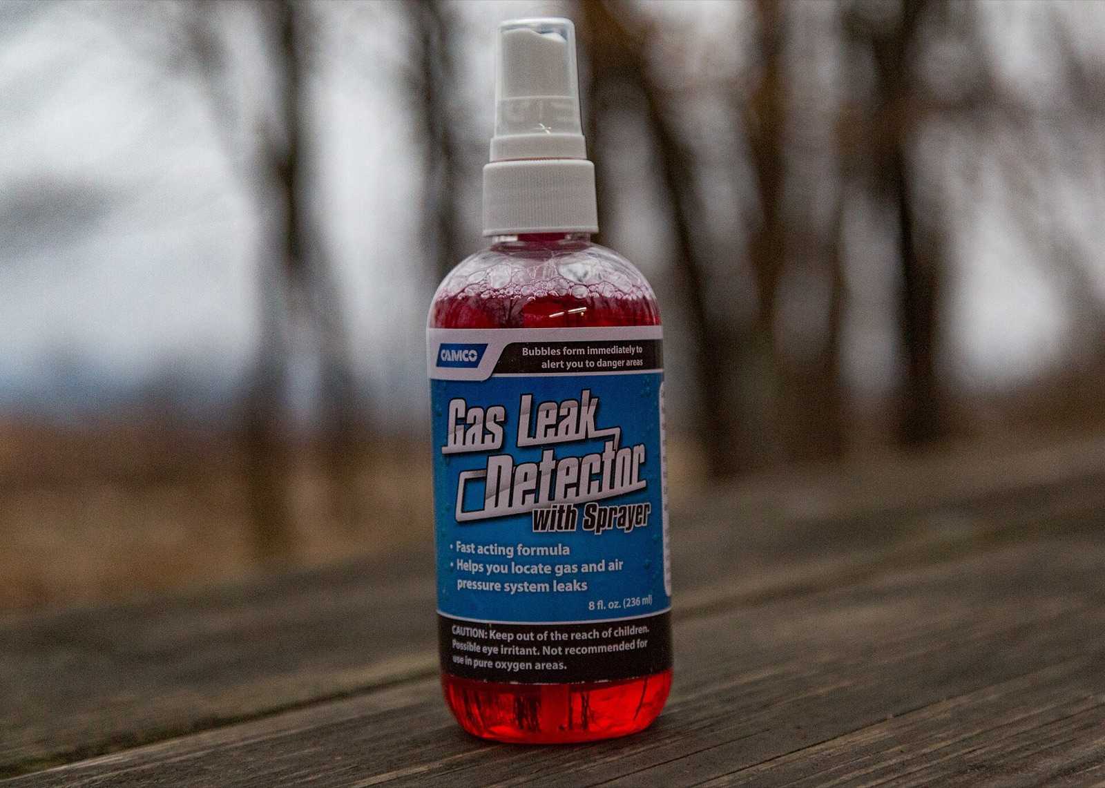 Spray bottle of gas leak detector solution for checking propane fittings, standing on a wooden table